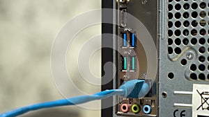 Male hand attaches blue ethernet cable to the back of computer. Close up footage