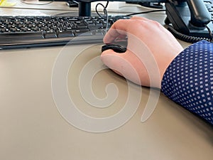 Male hand on a black computer mouse on the table in a modern business office