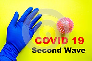 Male hand in a blue medical sterile glove near the core, virus, coronavirus on a yellow background. Copy Space. Covid-19