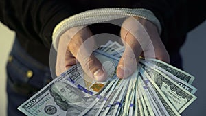 Male hand bound with the rope holding pile of money american dollar bank notes, financial rectrictions concept