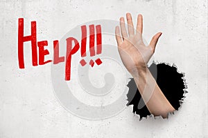 Male hand breaking white wall with red `Help` sign on white background