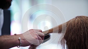 Male hand brushing womanâ€™s hair. Professional hairdresser used a brush