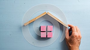 Male hand building a house of pink wooden blocks