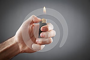 Male hand burning lighter in grey background