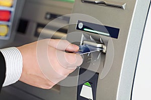 Male hand businessman inserts credit card into the ATM