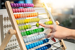 Male hand calculating beads on rainbow abacus