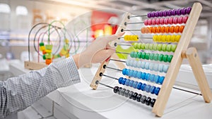 Male hand calculating beads on rainbow abacus