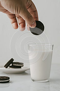 Male hand carrying a chocolate cookie to soak it in milk