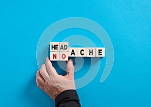 Male hand changes the word headache to no ache on blue background. Headache treatment and prevention