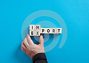 Male hand changes the word import to export on blue background. Industrial trade relations. Importing and exporting strategies