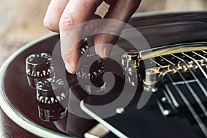 Male hand changing electric guitar settings. Tuning a timbre regulator photo