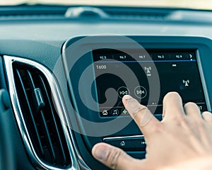 Male hand changing the radio station on car LCD infotainment screen