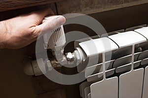 A male hand checks the heating on a white radiator.