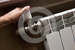 A male hand checks the heating on a white radiator.