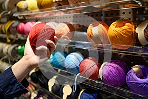 Male hand choosing yarn ball in knitting shop