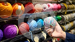 Male hand choosing yarn ball in knitting shop