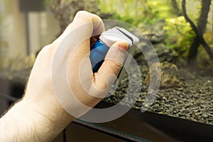 Male hand cleaning aquarium glass