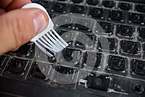 Male hand cleans dirty keyboard without keys