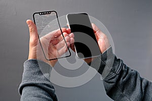 Male hand close-up holds mobile phone with a cracked protective glass screen, broken phone glass, cracked concept with a gadget,