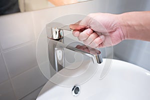 Male hand closing water tap in bathroom photo