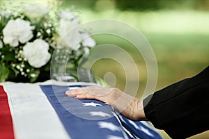 Male hand on coffin covered with American flag