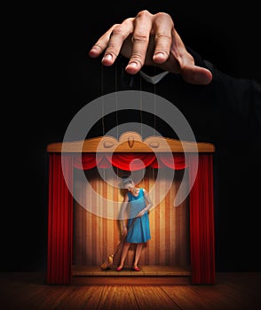 Male hand controlling a small woman puppet photo