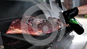 Male hand cooked beef steak meat piece outdoor grill barbecue sprinkling liquid oil sauce slowmo