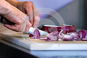 Male hand cutting - chopping red onions, sun light.