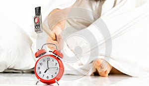 Male hand destroys alarm clock, white background.