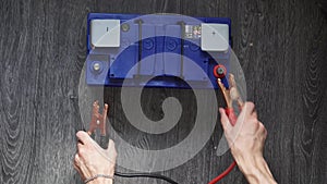 The male hand detach the terminals to the car`s batteries on a wooden background