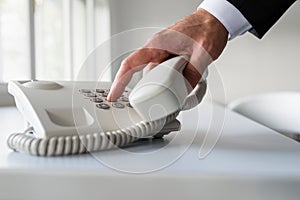 Male hand dialing a telephone number in order to make a phone ca