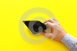 male hand directing single papaer boat on yellow background. concept of finding the right directon and moving ahead