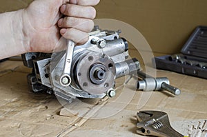 The male hand disassembles the high-pressure diesel fuel pump