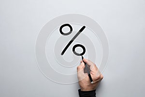 Male hand drawing a big percent sign on gray background with a pen. Discount, sale, profit or share