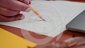 Male hand draws with slate pencil on a white sheet of paper. Drawing or sketching