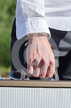 Male hand enchained to suitcase