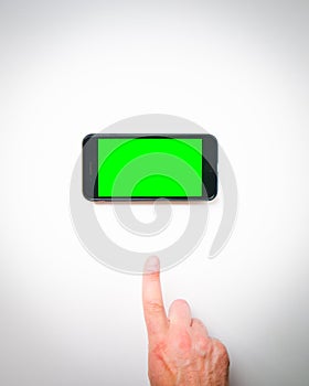 Male hand finger up to smartphone green screen on a white background curtains. Isolated blank space copypaste smartphone