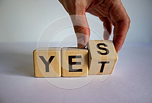 Male hand flips a cube and changes the expression YES to YET. Beautiful white background. Business concept