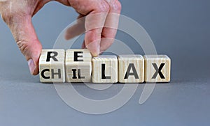 Male hand flips wooden cubes and changes the inscription `chillax` to `relax`. Beautiful grey background, copy space. Business