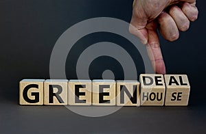 Male hand flips wooden cubes and changes the inscription `greenhouse` to `green deal`. Beautiful grey background, copy space
