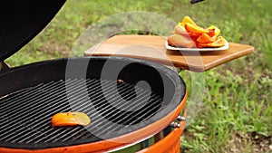 Male hand frying fresh juicy sweet pepper slice on barbecue turning vegetables using forceps