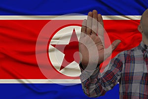 Male hand with a gesture of protest, oaths against the backdrop of the silk national flag of North Korea, the concept of denial