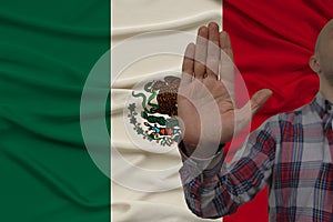 Male hand with a gesture of protest, oaths against the background of the silk national flag of Mexico, the concept of denial and