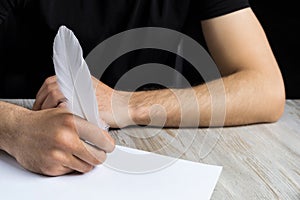 Male hand with a goose feather. Poetry and journalism symbol. The concept of writing texts