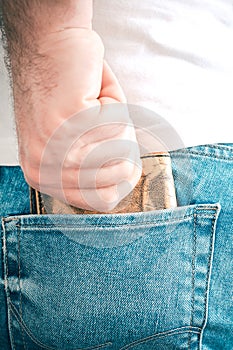 Male Hand Grabbing A Brown Leather Wallet In The Back Pocket Of A Jeans Trouser