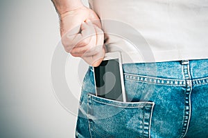 Male Hand Grabbing A Smartphone In The Left Back Pocket Of A Jeans Trouser