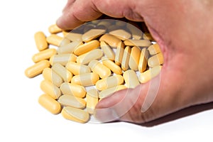 Male hand grabs yellow Multi-vitamin B focused on the pills isolated on white