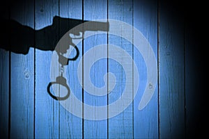 Male Hand with Gun and Handcuffs on Natural Wood Background, XXX