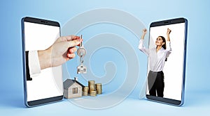 Male hand handing key from smartphone to happy businesswoman with house and coins on blue background. Online home purchase, buy