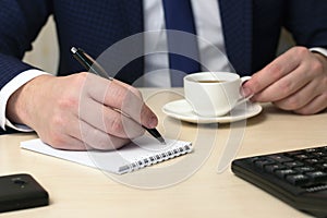 Male hand with the handle and a coffee cup